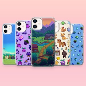 Peut inclure: Cinq coques de téléphone avec différents motifs. L'une présente un paysage avec une maison et des montagnes. Une autre a un motif de raisin pixélisé. D'autres coques ont des motifs d'animaux et de pierres précieuses. Les coques sont sur un fond rose.