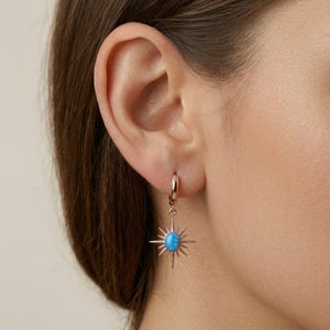 May include: A white ceramic mug with a black handle and the text "But First, Coffee" in a bold, black font. The mug is set against a blurred background, suggesting a cozy setting.