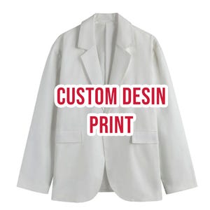 May include: A solid white blazer featuring long sleeves, a notched lapel collar, and two front flap pockets. The center of the garment displays the red text CUSTOM DESIN PRINT in a bold, sans-serif font with a white outline for high visibility.