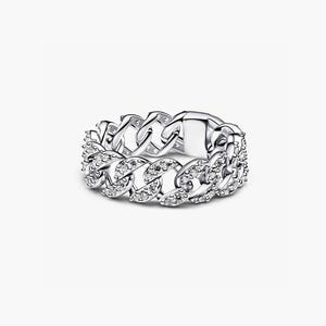 Può includere: Un anello a catena color argento composto da una serie di maglie metalliche intrecciate. La superficie anteriore delle maglie è incastonata con numerose piccole pietre chiare e scintillanti che catturano la luce, creando un aspetto metallico testurizzato.