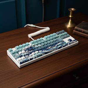 May include: A white mechanical keyboard with keycaps in shades of blue and white, creating a gradient effect. The design resembles ocean waves. The keyboard sits on a dark wooden desk, with a coiled white cable.