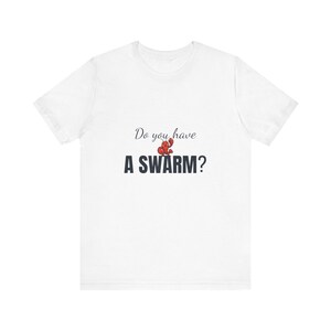 Op de afbeelding: Wit T-shirt met de tekst "Do you have A SWARM?" in een donkerblauwe letter. Een rood-oranje illustratie van een rivierkreeft staat boven het woord "SWARM".
