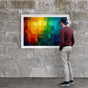 May include: A framed abstract art piece with a vibrant, colorful design of overlapping shapes in shades of red, orange, yellow, green, and blue. The artwork is displayed on a gray concrete wall.