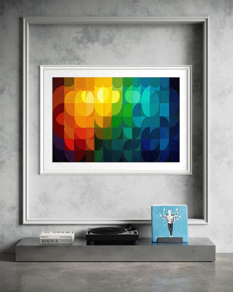 May include: A framed abstract art print with a vibrant, colorful design. The artwork features a geometric pattern of overlapping shapes in a spectrum of colors, including red, orange, yellow, green, and blue. A record player and books are on a shelf below.