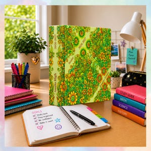 May include: A bright yellow binder with a dense green and orange floral pattern, labeled Austin High, 2026-2027, Senior, and Jennifer Friend. It sits on a desk with a spiral notebook containing a goals list, a black pen, and four colored books.