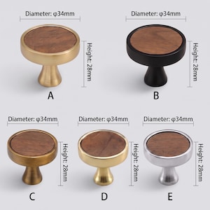 May include: Five round cabinet knobs labelled A to E, each featuring a circular wood grain inlay and a metal base. Each knob has a diameter of 34mm and a height of 28mm. The finishes include brushed gold, matte black, antique brass, polished gold, and silver.