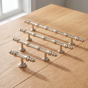 May include: A set of four silver-toned metal cabinet pulls in varying lengths, each featuring a segmented bamboo-inspired design with a polished finish and two circular mounting bases, arranged diagonally from smallest to largest.