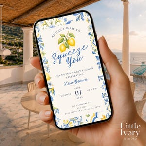 Può includere: Un invito digitale per baby shower visualizzato sullo schermo di uno smartphone, con sfondo color crema, bordi floreali blu e gialli in stile mediterraneo, due limoni gialli e il testo We Can't Wait To Squeeze You per Lisa Brown.