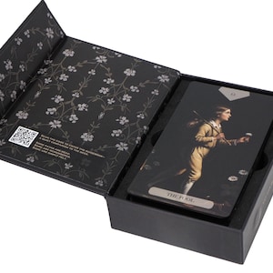May include: A black tarot card box with a floral design on the inner lid. Inside, tarot cards feature a vintage illustration of a person in a yellow outfit. The card is labelled "THE FOOL".