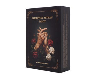 May include: A black tarot card box with the title "THE DIVINE ARTISAN TAROT" in gold lettering. The box features an illustration of clasped hands surrounded by red and white roses. The box is rectangular and has gold decorative accents.