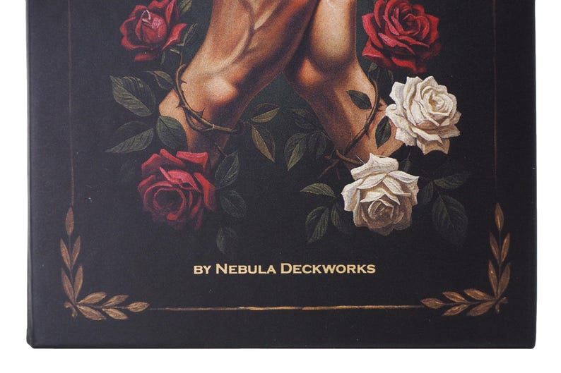 May include: A dark box with an artistic illustration of two arms intertwined, encircled by a thorny vine, surrounded by red and white roses. The text "BY NEBULA DECKWORKS" is displayed in gold lettering.