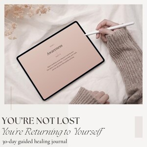 Peut inclure: Une tablette num&eacute;rique affichant le mot "Awareness" sur un &eacute;cran rose, avec un stylet au-dessus. Le texte "YOU'RE NOT LOST You're Returning to Yourself 30-day guided healing journal" est en dessous.