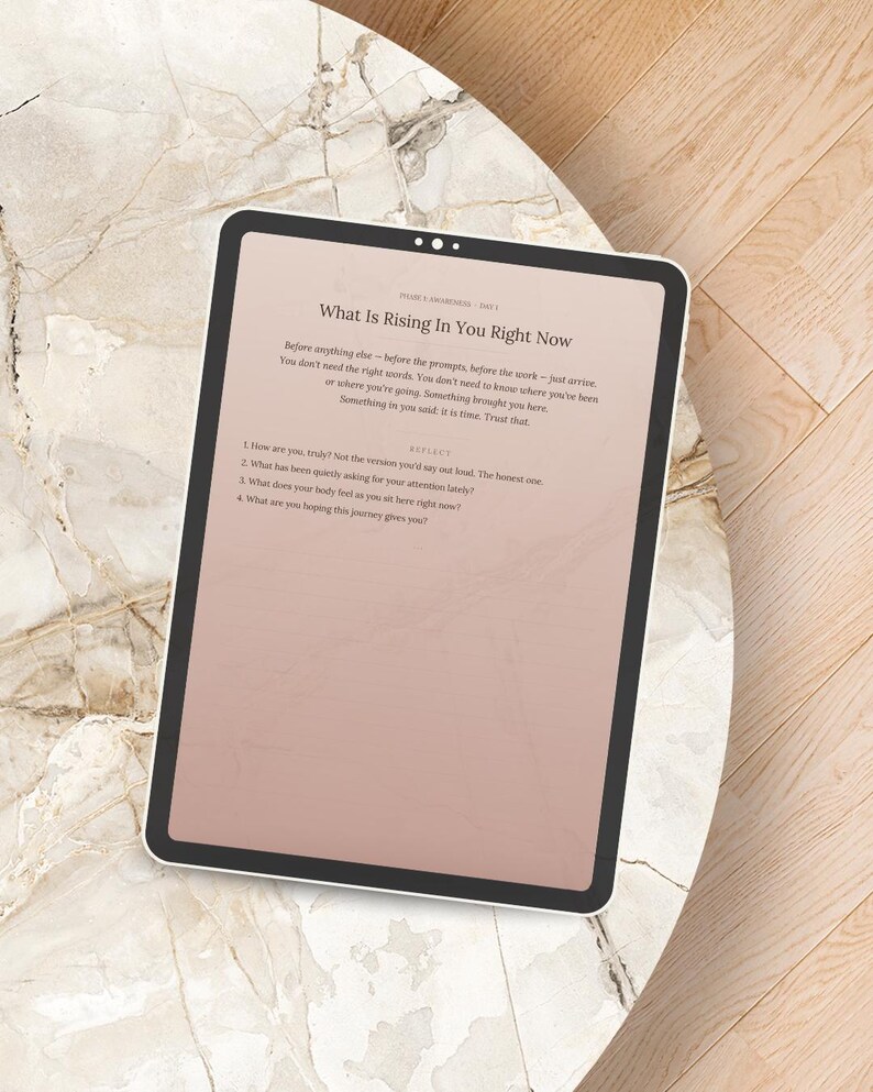 Peut inclure: Une tablette num&eacute;rique affichant le texte "What Is Rising In You Right Now" sur un fond rose clair. La tablette est pos&eacute;e sur une surface &agrave; motifs de marbre. Le texte comprend des invites &agrave; la r&eacute;flexion personnelle.