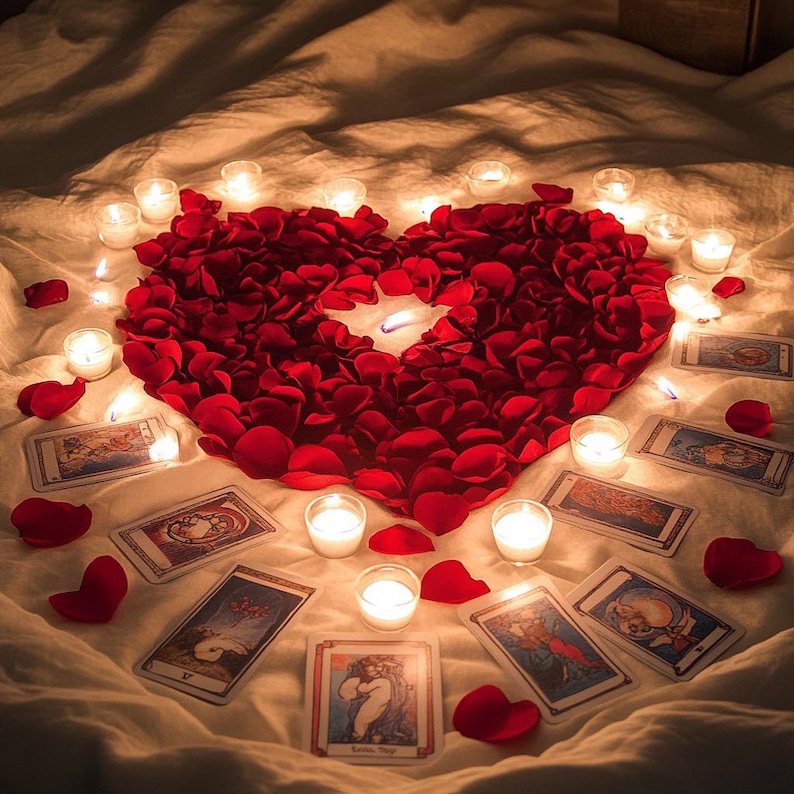 May include: A romantic scene featuring a heart shape made of red rose petals, surrounded by lit candles and tarot cards. The arrangement is set on a white sheet, creating a warm and intimate ambiance.