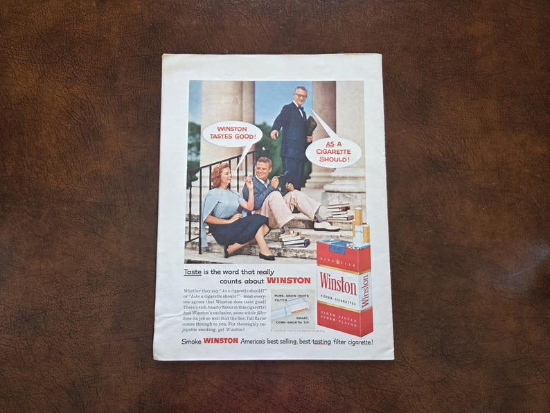 Puede incluir: Un anuncio de revista antiguo de cigarrillos Winston con un hombre y una mujer sentados en escalones de piedra y un hombre detr&aacute;s. El texto dice WINSTON TASTES GOOD! AS A CIGARETTE SHOULD! e incluye una cajetilla de cigarrillos Winston roja.