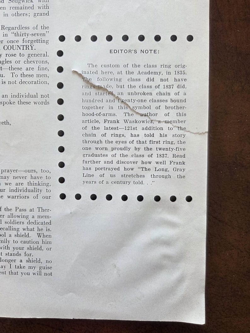 Puede incluir: Un documento de papel blanco con una secci&oacute;n rasgada y texto negro titulado EDITOR'S NOTE. El texto trata sobre la historia de los anillos de clase en la Academia desde 1835, mencionando a Frank Waskowicz y la 121.&ordf; adici&oacute;n a la cadena.