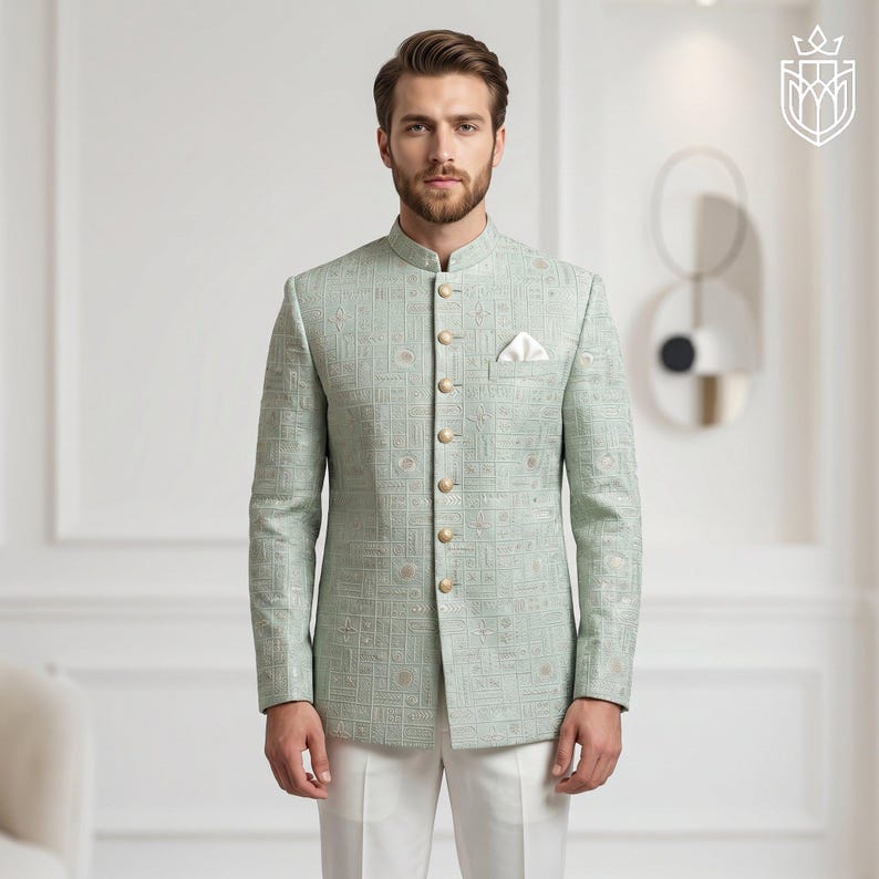K&ouml;nnte beinhalten: Hellgr&uuml;ne Jacke mit Stehkragen und goldenen Kn&ouml;pfen. Die Jacke hat ein geometrisches Muster und ein Einstecktuch. Sie wird mit einer wei&szlig;en Hose getragen. Der Stil ist formell und elegant.