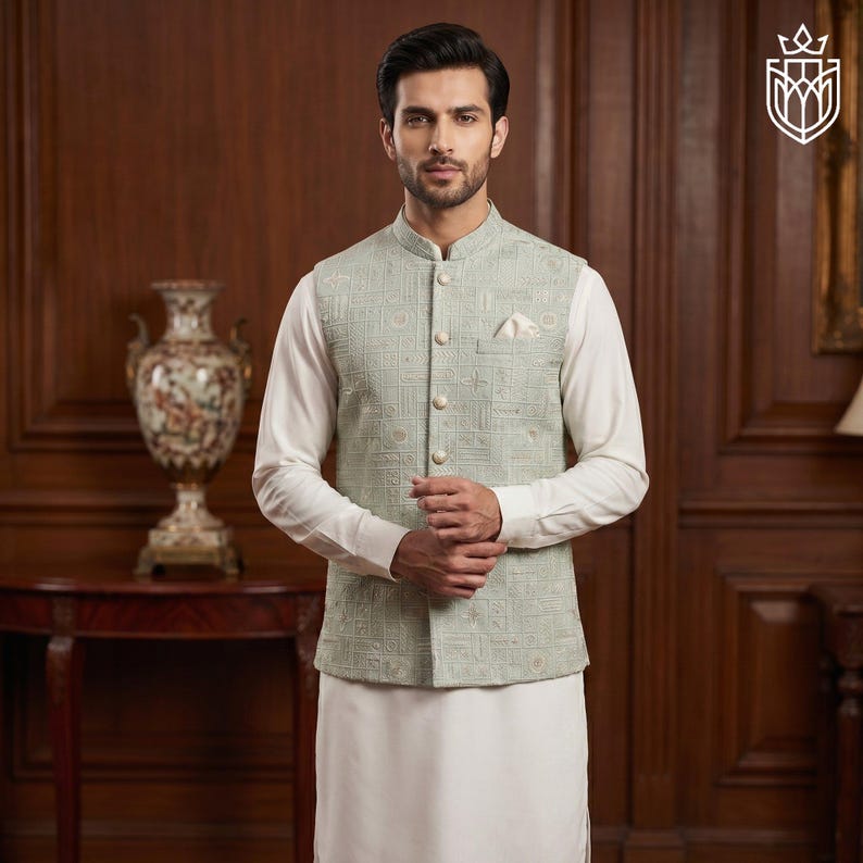May include: A light green embroidered vest with a mandarin collar, worn over a white long-sleeved shirt and white pants. The vest has a geometric pattern and is buttoned up. A pocket square is visible. The outfit is formal wear.