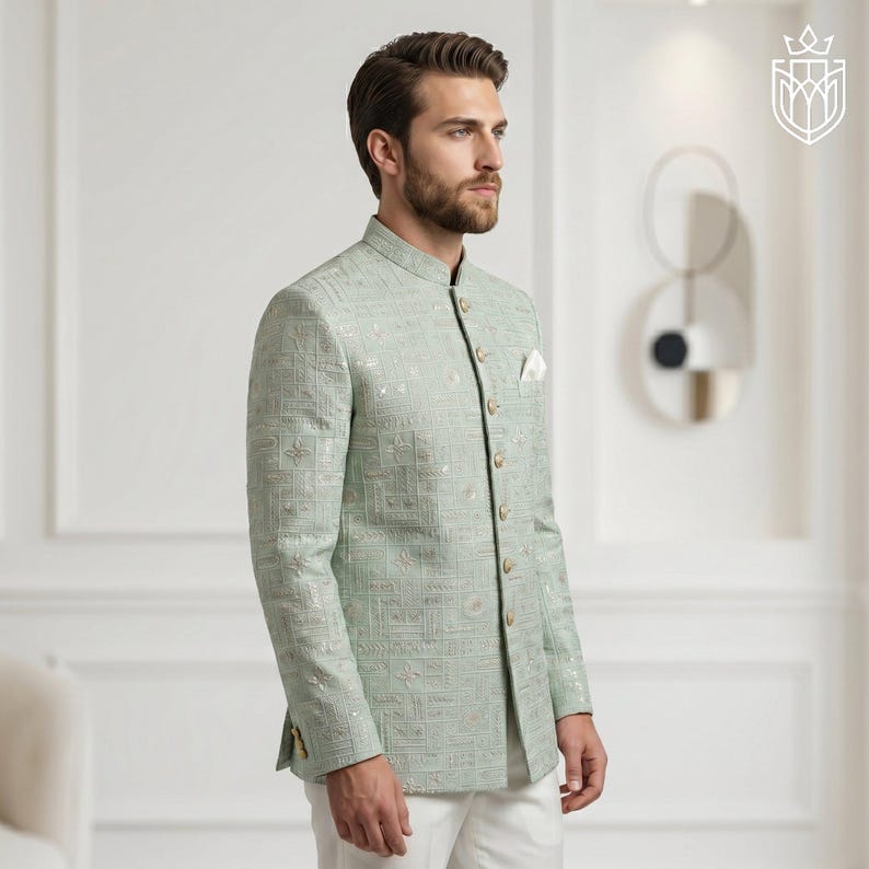 K&ouml;nnte beinhalten: Hellgr&uuml;ne Jacke mit Stehkragen und dezentem geometrischem Muster. Die Jacke hat goldfarbene Kn&ouml;pfe und ein Einstecktuch. Das Outfit wird durch eine wei&szlig;e Hose erg&auml;nzt. Die Jacke ist ein formelles Kleidungsst&uuml;ck.