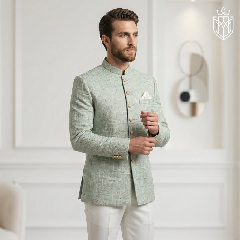 K&ouml;nnte beinhalten: Hellgr&uuml;ne Jacke mit Stehkragen und dezentem geometrischem Muster. Die Jacke hat goldfarbene Kn&ouml;pfe und wird mit einer wei&szlig;en Hose kombiniert. Ein wei&szlig;es Einstecktuch ist sichtbar. Die Jacke ist ein formeller Stil.