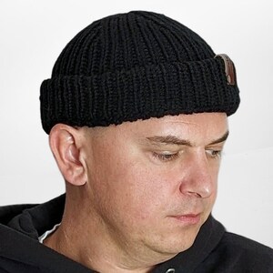 a man wearing a black hat with a button on it