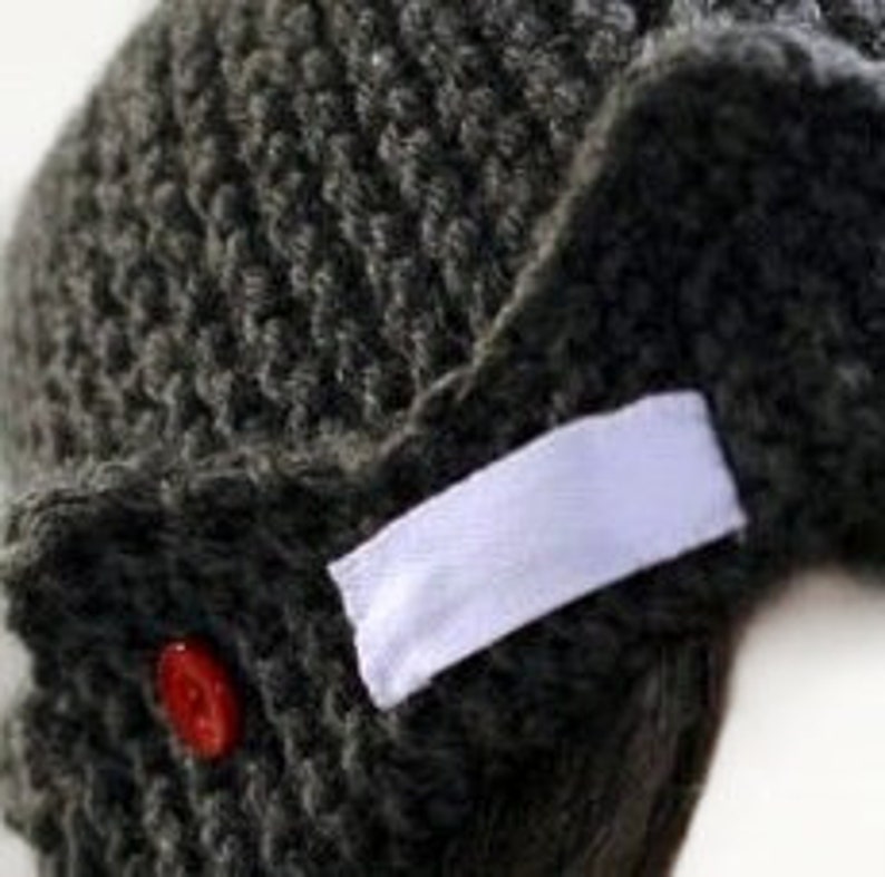 a close up of a knitted hat with a red button