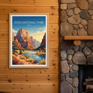 May include: Framed art print of Zion National Park in Utah. The artwork depicts a scenic landscape with towering red rock formations, a river, and a blue sky. The print is in a wooden frame and hangs on a wood-paneled wall.