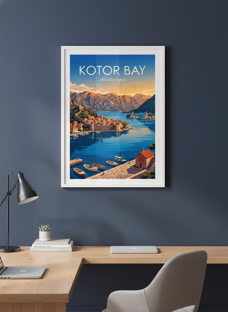 May include: Framed art print of Kotor Bay, Montenegro. The artwork depicts a coastal town with boats on the water, mountains in the background, and the text "Kotor Bay Montenegro" at the top. The color palette includes blues, oranges, and greens.