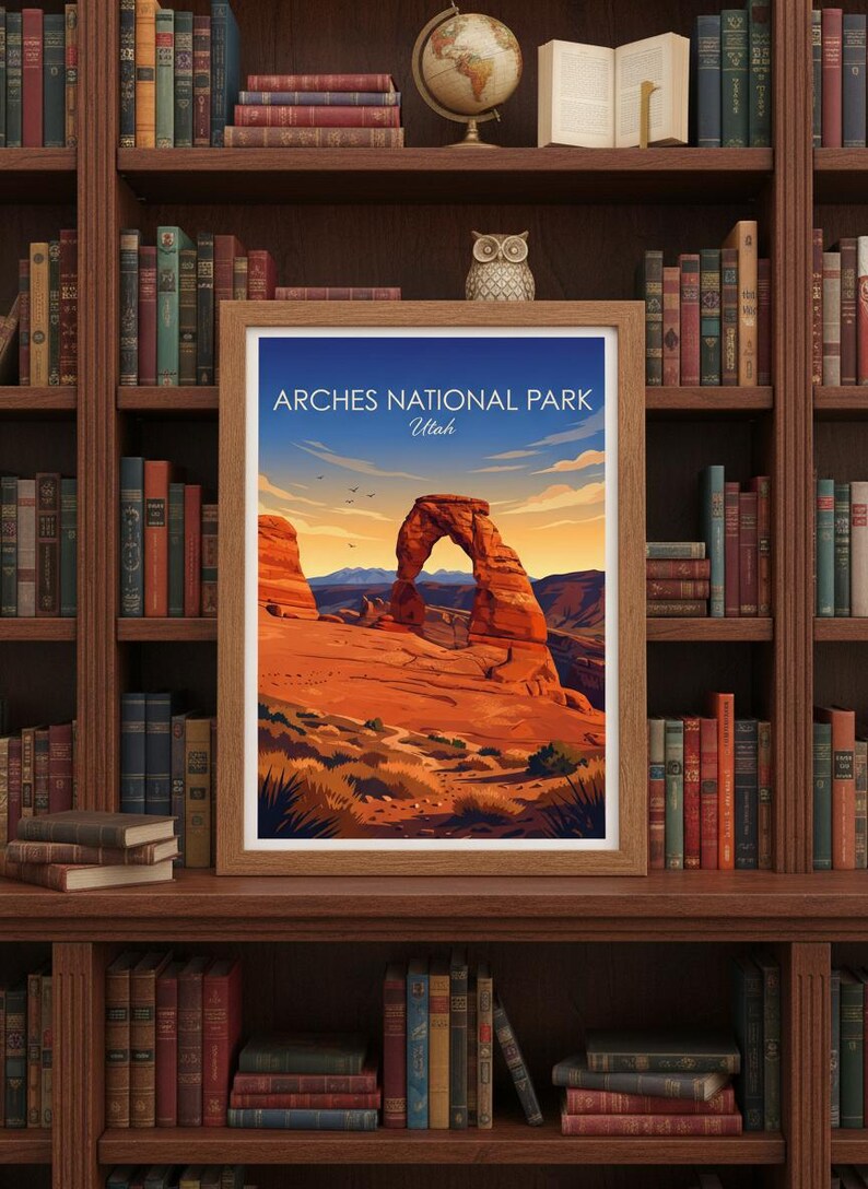 May include: Framed art print featuring a landscape of Arches National Park in Utah. The artwork depicts a large sandstone arch under a blue sky with the text "Arches National Park Utah". The print is displayed on a wooden bookshelf.