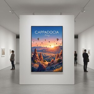 May include: A framed art print of Cappadocia, Turkey, featuring a vibrant sunrise with hot air balloons. The artwork depicts unique rock formations and a colorful sky, displayed in a gallery setting.