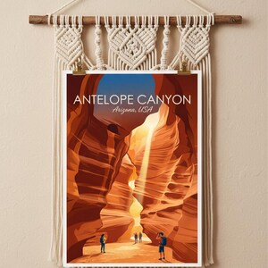 May include: A rectangular print of Antelope Canyon, Arizona, USA, featuring orange sandstone walls and a light beam, suspended from a cream-colored macrame wall hanging with a wooden dowel and fringe. The print displays the text Antelope Canyon Arizona, USA.