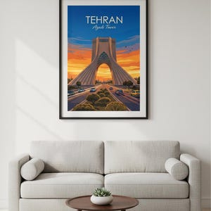 May include: Framed art print of the Azadi Tower in Tehran, Iran. The image shows the tower with a road leading towards it, set against a sunset sky. The print is displayed above a grey sofa and a round coffee table.