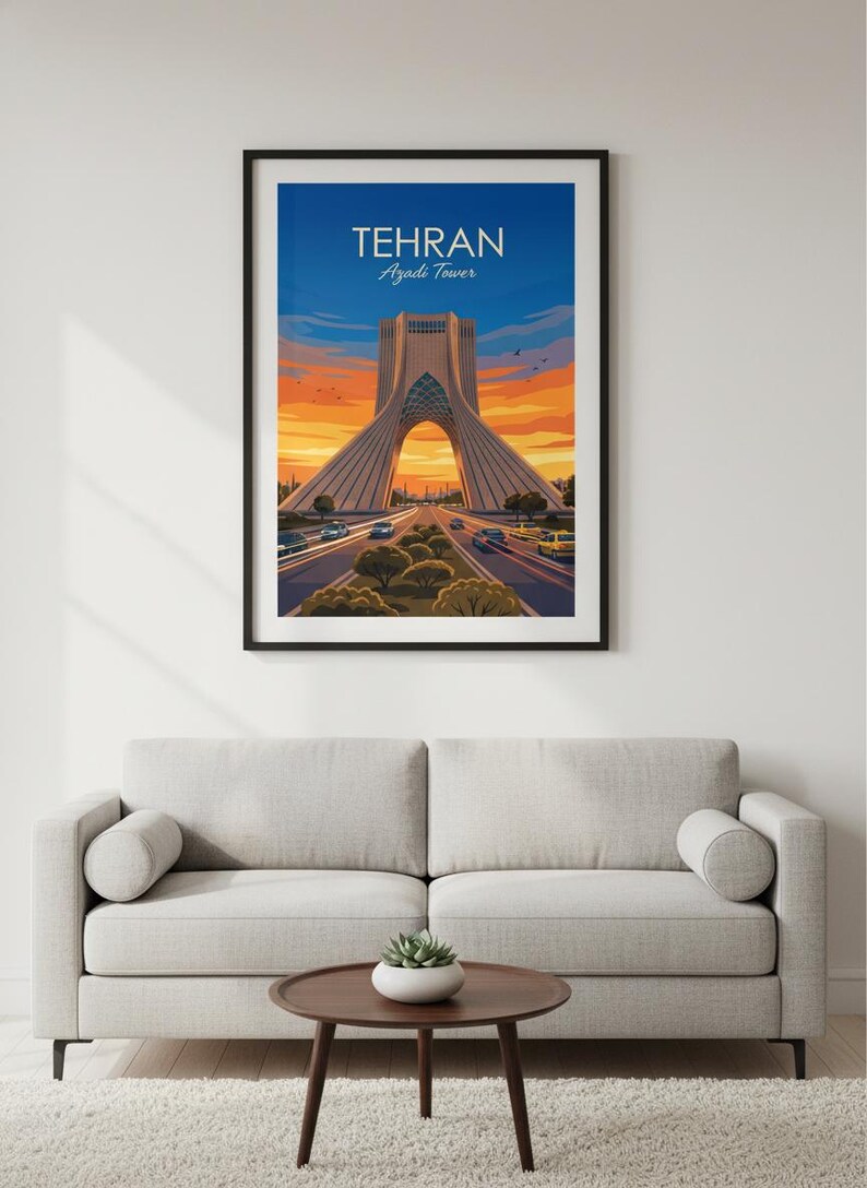 May include: Framed art print of the Azadi Tower in Tehran, Iran. The image shows the tower with a road leading towards it, set against a sunset sky. The print is displayed above a grey sofa and a round coffee table.