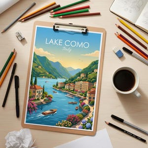 May include: A clipboard shows a vibrant illustration of Lake Como, Italy, with boats on the water and buildings along the shore. Pencils, pens, and a coffee cup are arranged around the clipboard on a wooden surface. The text "LAKE COMO Italy" is visible.