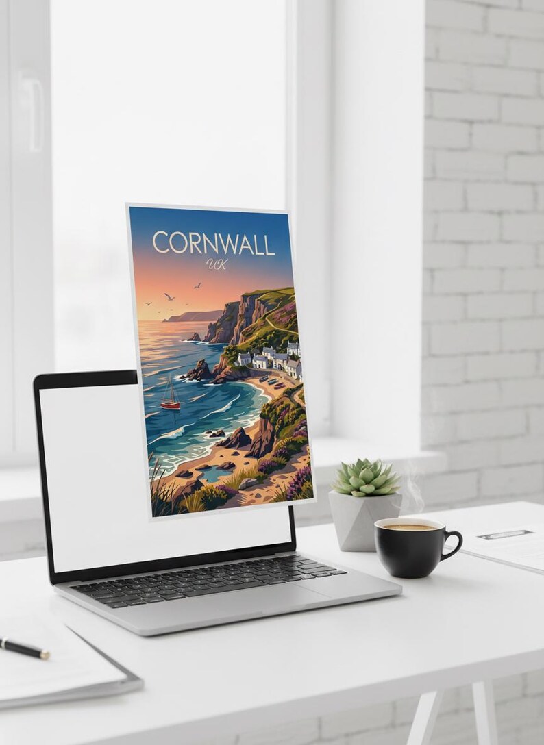 May include: A laptop displays a travel poster for Cornwall, UK, featuring a coastal scene with a red sailboat, cliffs, and a village. The poster is set against a blue sky with the text "Cornwall UK". A succulent and coffee cup are on the desk.