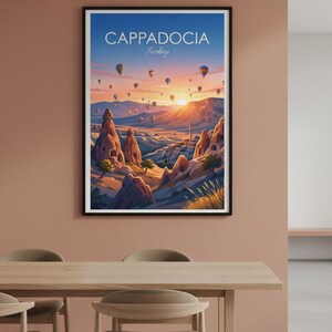 May include: A framed art print featuring a vibrant landscape of Cappadocia, Turkey, with hot air balloons floating in a sunset sky. The print includes the text "Cappadocia Turkey". The artwork depicts unique rock formations and a village.