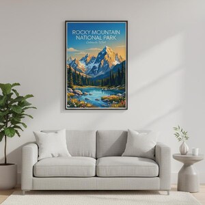 May include: A framed wall art print featuring a landscape illustration of Rocky Mountain National Park, Colorado, USA. The image displays snow-capped mountains, a blue lake, evergreen trees, and colourful wildflowers under a clear sky.