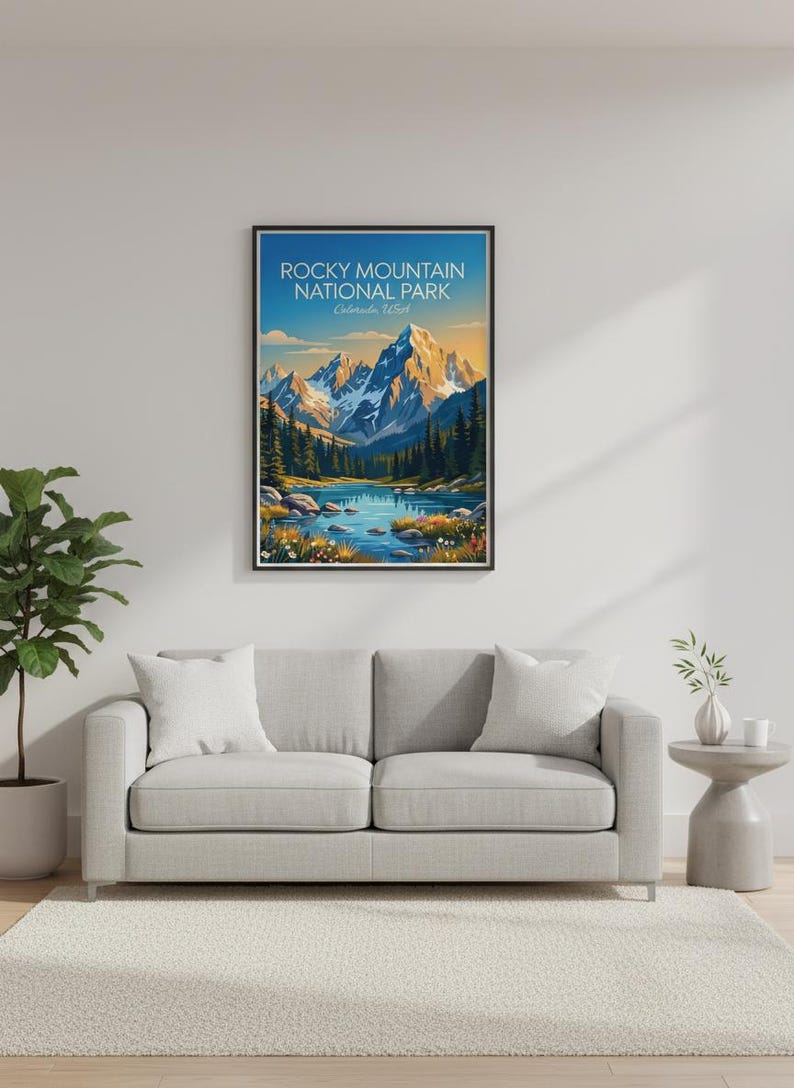 May include: A framed wall art print featuring a landscape illustration of Rocky Mountain National Park, Colorado, USA. The image displays snow-capped mountains, a blue lake, evergreen trees, and colourful wildflowers under a clear sky.