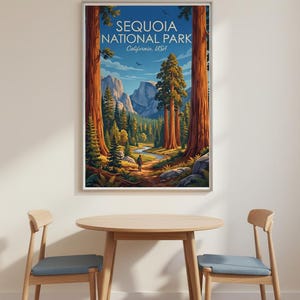 Op de afbeelding: Een ingelijste print van Sequoia National Park, Californi&euml;, VS. De illustratie toont een vallei met sequoia's, een rivier en bergen. Een persoon is te zien op een pad. De print wordt weergegeven boven een houten tafel en stoelen.