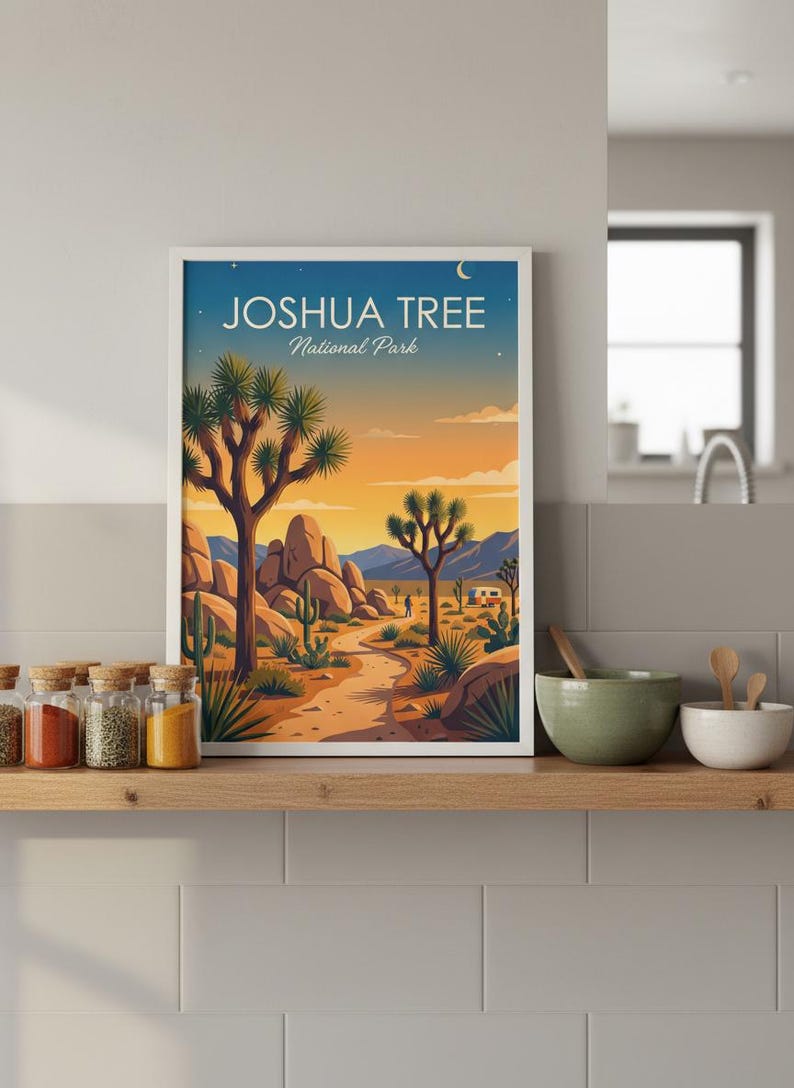May include: A framed art print featuring a desert landscape with Joshua trees, cacti, and a winding path. The artwork displays the text "JOSHUA TREE National Park" against a sunset sky. The print is displayed on a wooden shelf.