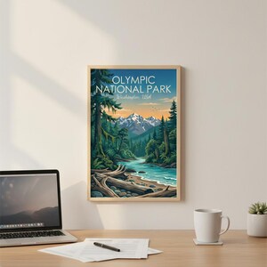 May include: Framed art print featuring a scenic view of Olympic National Park in Washington, USA. The artwork depicts a river flowing through a lush forest with snow-capped mountains in the background. The print is in a wooden frame.