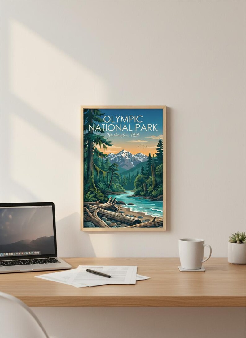 May include: Framed art print featuring a scenic view of Olympic National Park in Washington, USA. The artwork depicts a river flowing through a lush forest with snow-capped mountains in the background. The print is in a wooden frame.