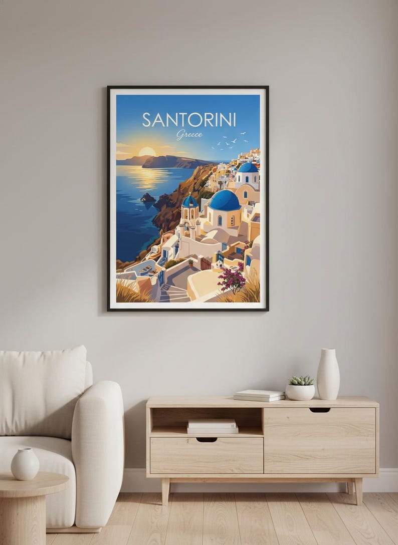 Puede incluir: Impresi&oacute;n enmarcada de Santorini, Grecia. La imagen presenta edificios blancos con c&uacute;pulas azules en un acantilado con vistas al mar Egeo. El cielo es un degradado de azul y dorado, con el texto "SANTORINI Greece" en la parte superior.