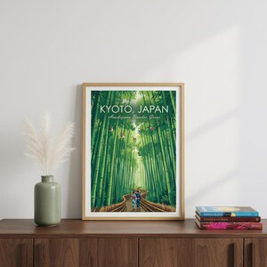 May include: Framed art print featuring a vibrant illustration of the Arashiyama Bamboo Grove in Kyoto, Japan. The artwork depicts a path winding through towering green bamboo stalks, with the text "KYOTO, JAPAN" at the top.