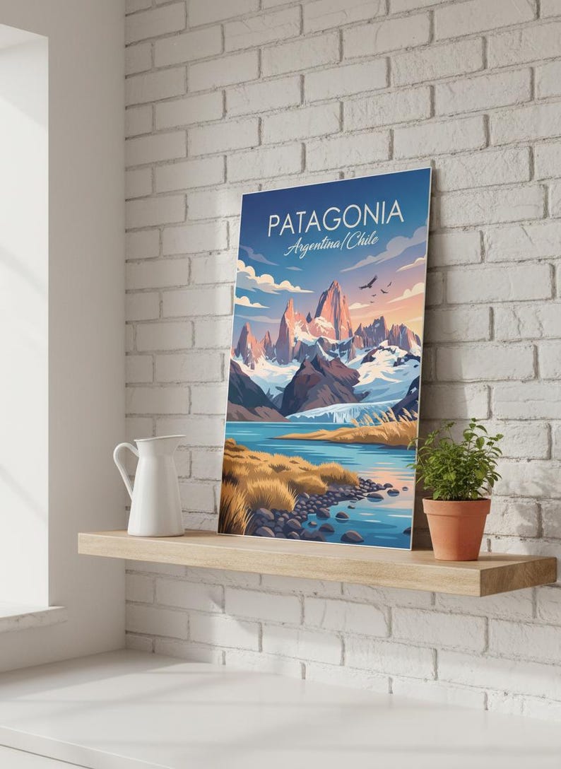 Op de afbeelding: Een ingelijste kunstdruk van Patagoni&euml;, Argentini&euml;/Chili, met een bergketen, een meer en een blauwe lucht. De print staat op een houten plank met een witte kan en een plant in een pot. De tekst "PATAGONIA" staat bovenaan.