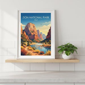 May include: A framed art print featuring a landscape illustration of Zion National Park, Utah, with towering red rock cliffs, a winding blue river, and desert vegetation under a clear sky. The text Zion National Park Utah is printed at the top.