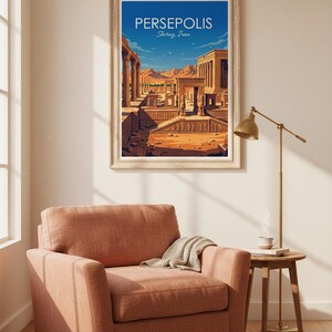 May include: A framed art print of Persepolis, Shiraz, Iran, hangs above a coral-colored armchair. The print depicts an ancient city with columns and structures under a blue sky. A small side table and lamp are next to the chair.