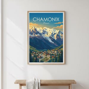 May include: Framed art print of Chamonix, France, depicting a mountain landscape with snow-capped peaks, a village in a valley, and the text "CHAMONIX France" against a blue sky.