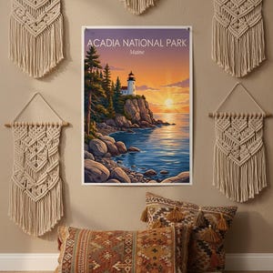 Puede incluir: Un estampado enmarcado del Parque Nacional Acadia en Maine, con un faro en una costa rocosa al atardecer. La escena est&aacute; rodeada de tapices de macram&eacute; beige y cojines decorativos con borlas.