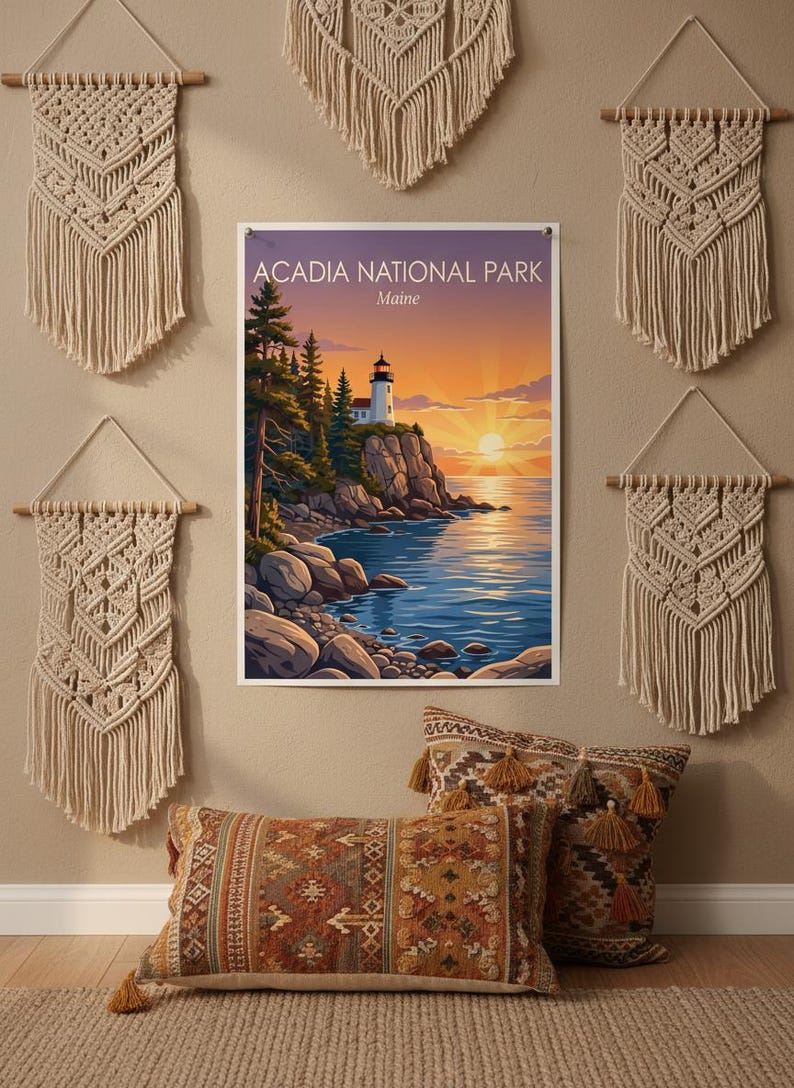 Puede incluir: Un estampado enmarcado del Parque Nacional Acadia en Maine, con un faro en una costa rocosa al atardecer. La escena est&aacute; rodeada de tapices de macram&eacute; beige y cojines decorativos con borlas.